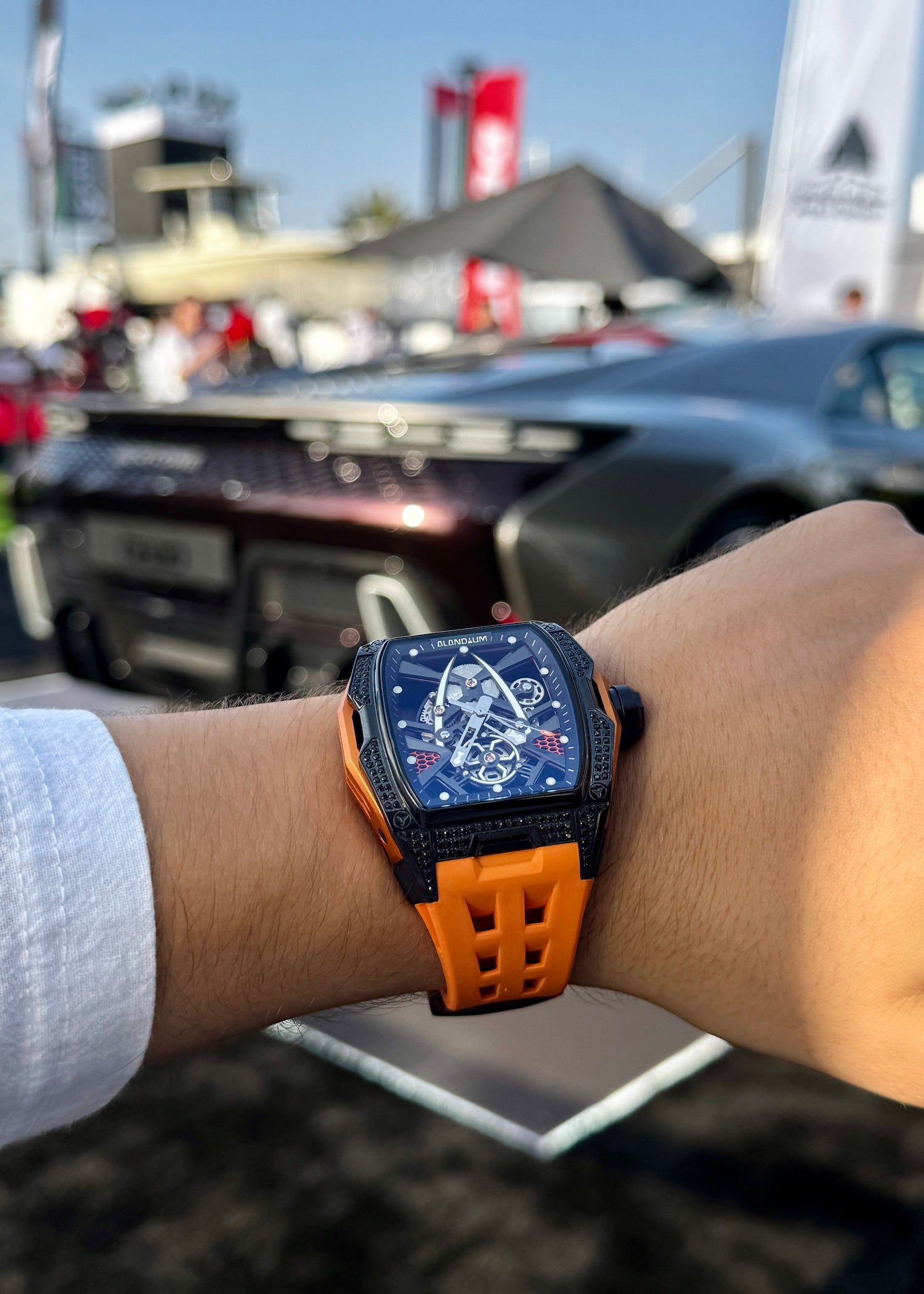 Person wearing a watch with an orange strap in an outdoor setting