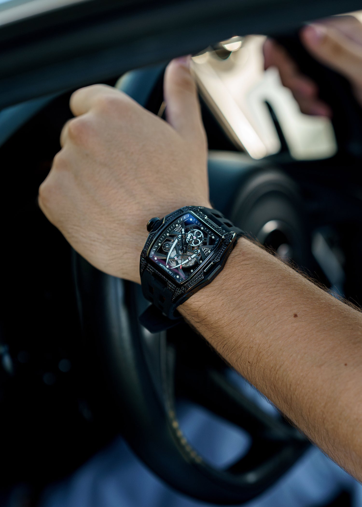 Person wearing a black luxury watch inside a car